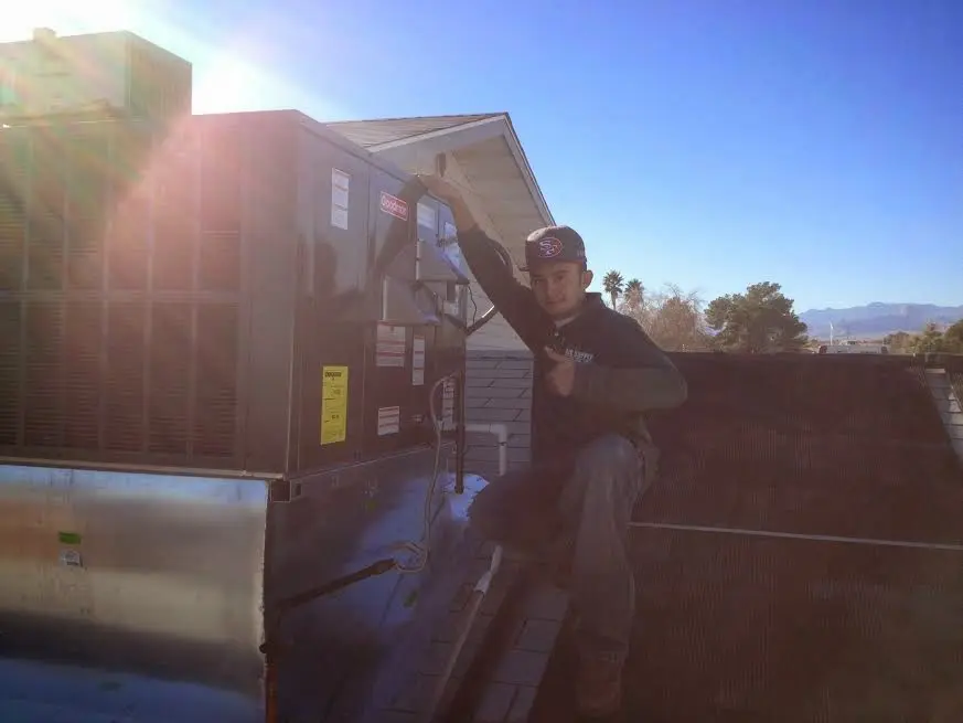 HVAC technician performing AC Tune-Up on a rooftop unit in Bedford